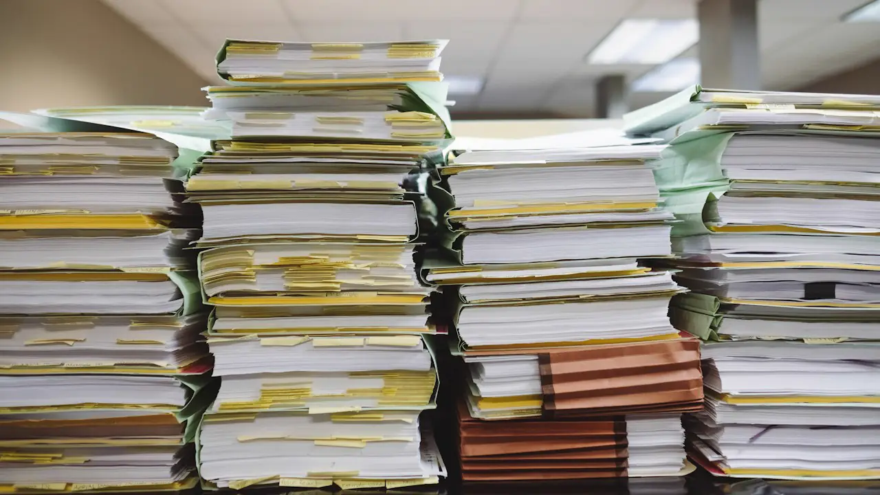 Tall stacks of paper files and folders on an office desk