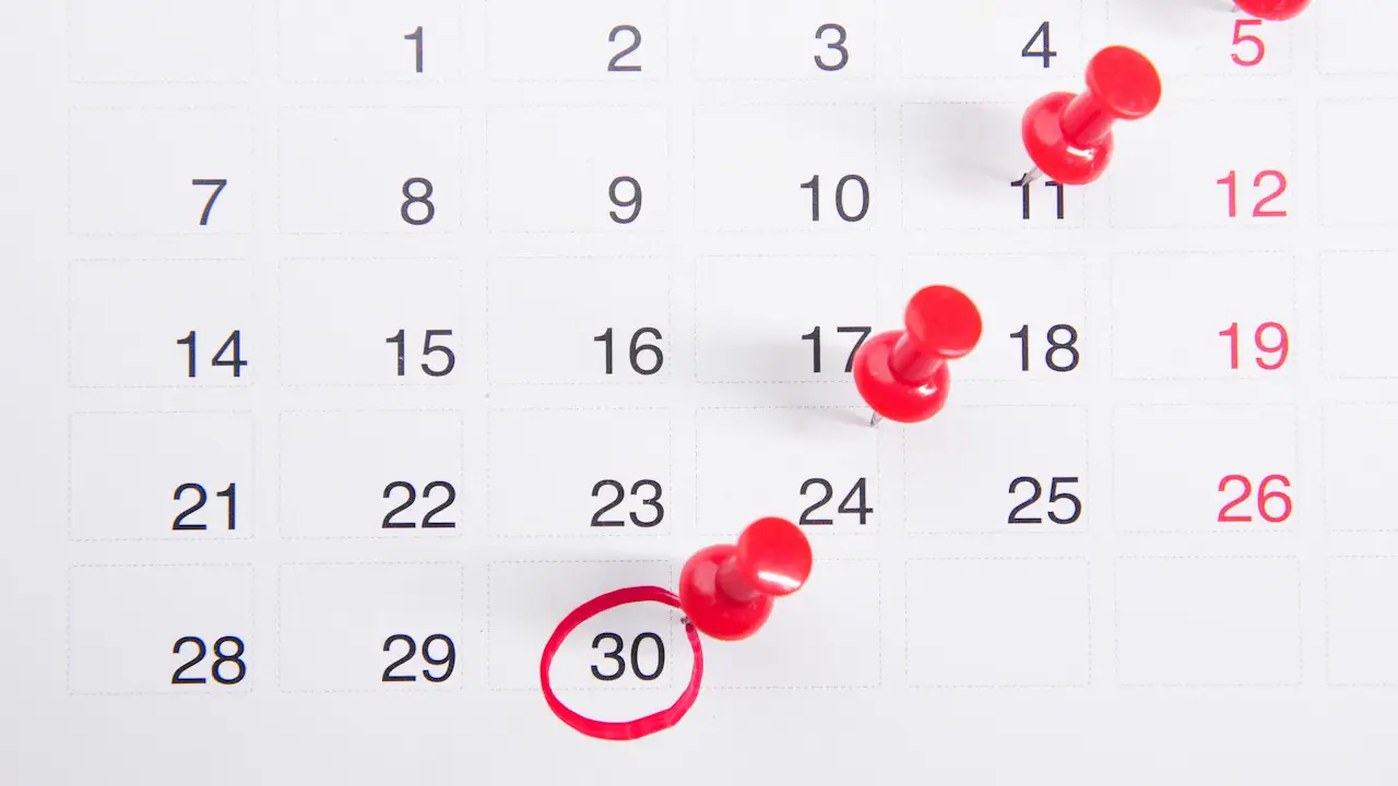 A monthly calendar with red pins marking several dates and the 30th circled