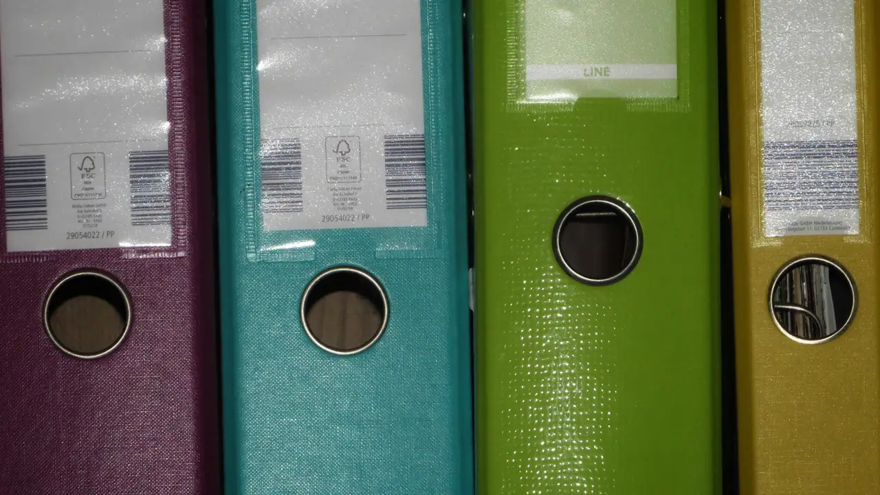 Four office binders in purple, teal, green and yellow standing side by side