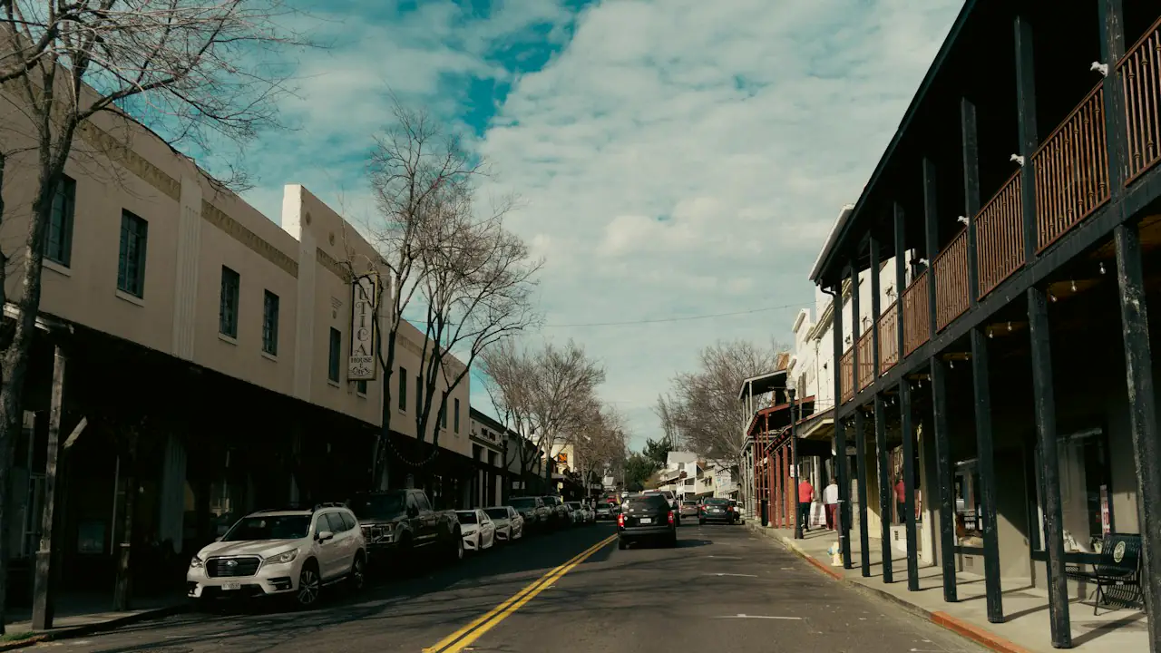 A main street lined with two storey commercial buildings and covered balconies under a blue sky