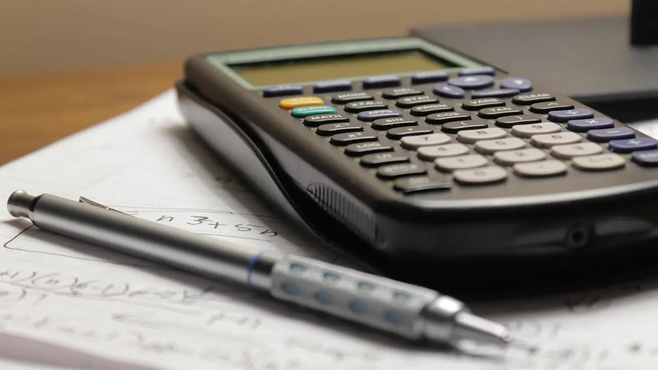 A calculator and a pen resting on printed figures
