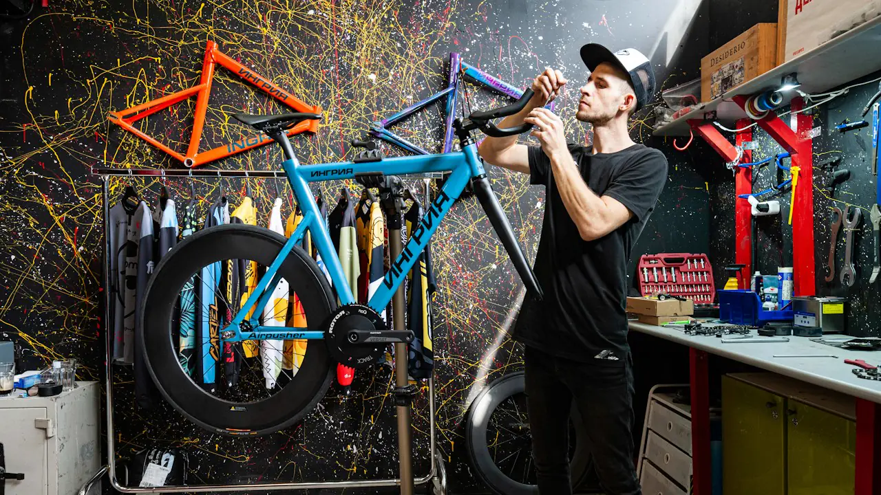 A mechanic tuning a bicycle in a colourful repair shop