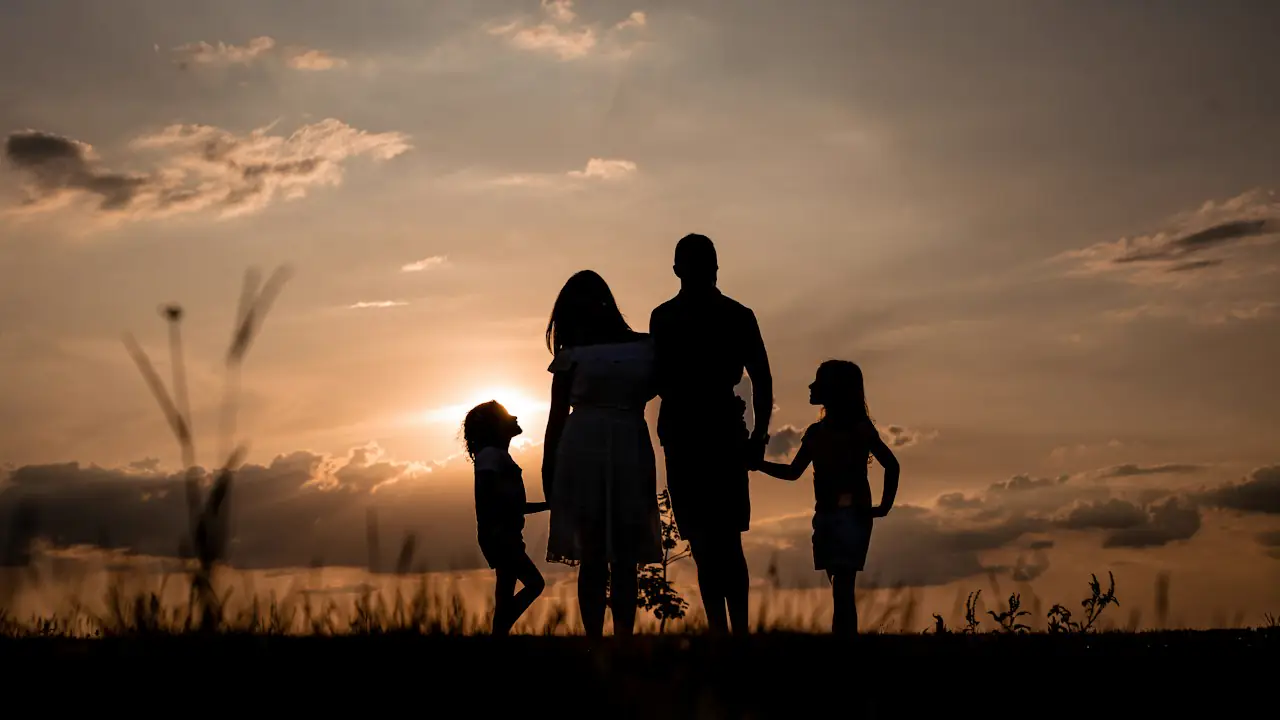 A family holding hands in silhouette at sunset