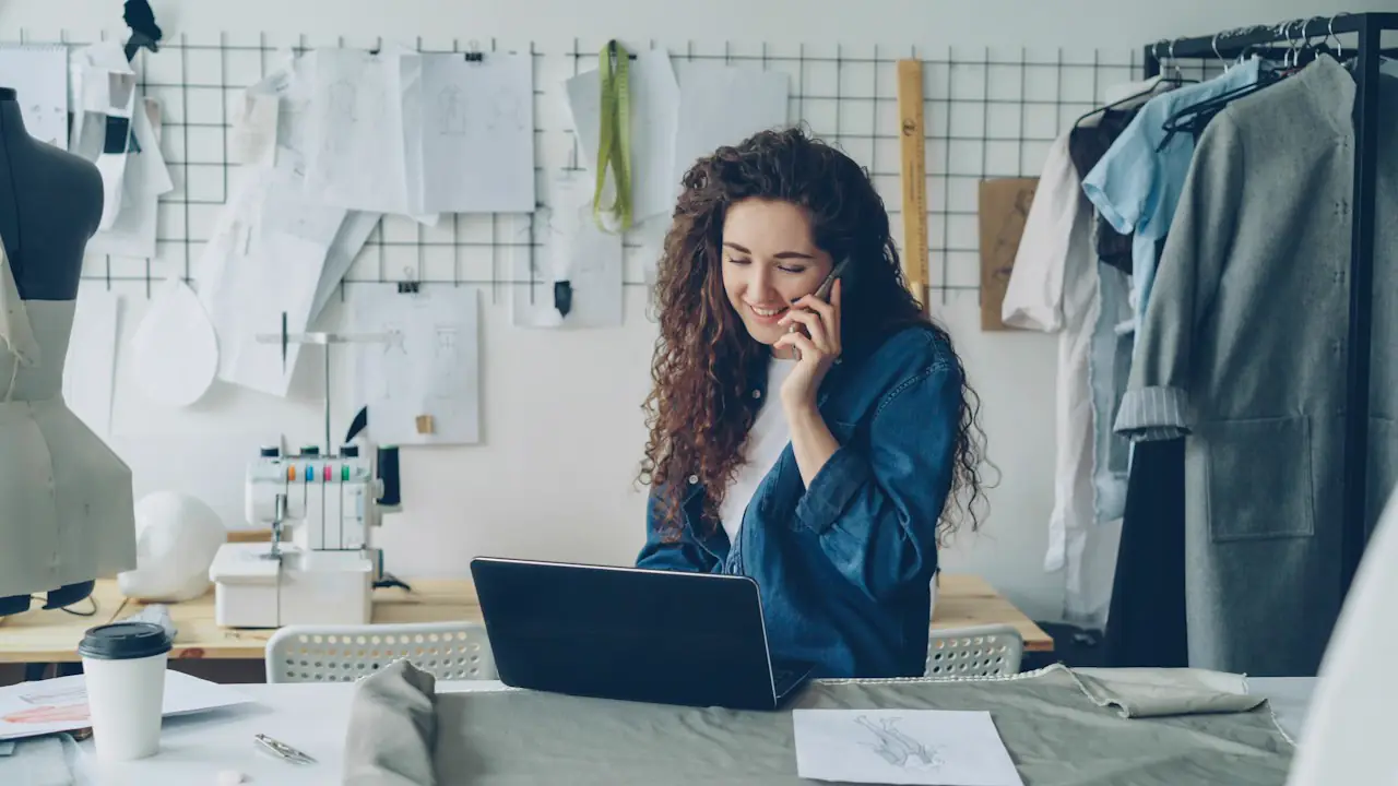 A smiling designer on the phone at her studio desk