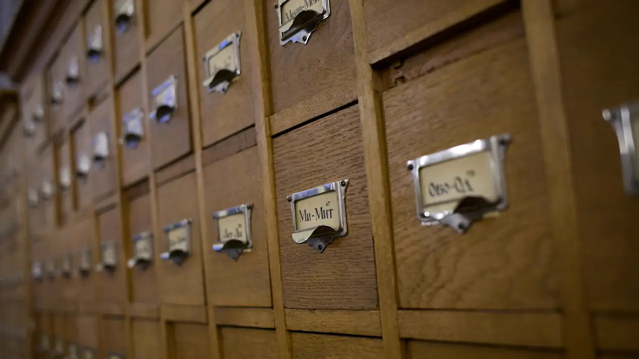 Rows of wooden card catalogue drawers with metal label holders