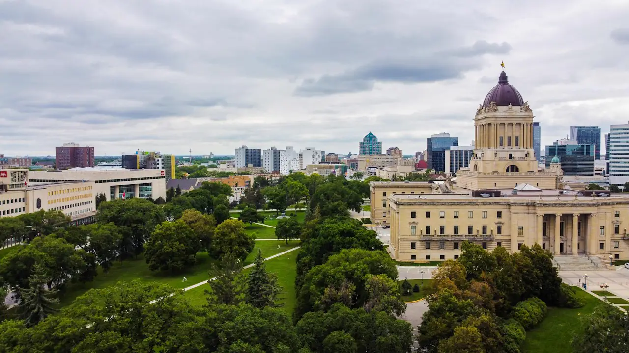 The Manitoba Legislative Building among trees with downtown Winnipeg behind