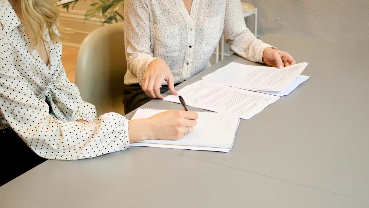 Two people reviewing and signing documents at a table