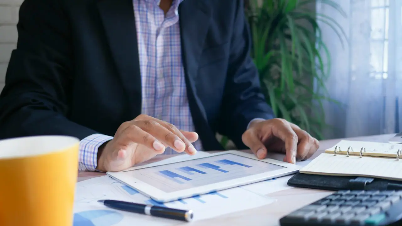 A professional reviewing charts on a tablet beside a calculator