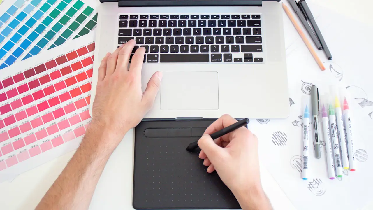A designer working on a drawing tablet beside colour swatches