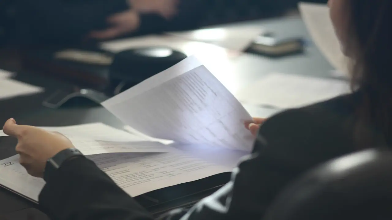 A person reading through a document at a dark table