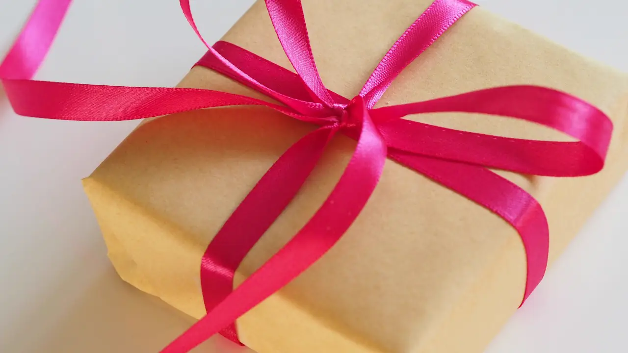 A gift wrapped in brown paper and tied with a bright pink ribbon