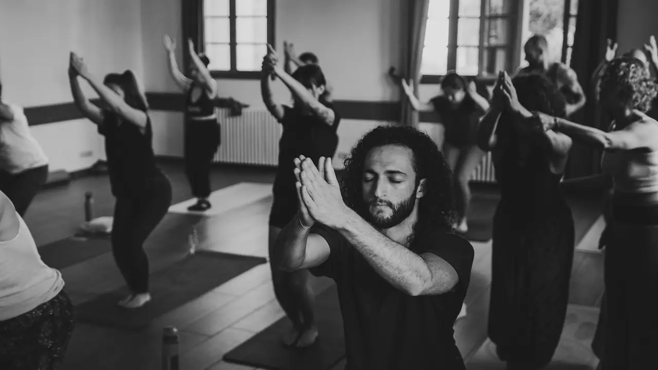 A yoga class practising a standing pose together in a bright studio
