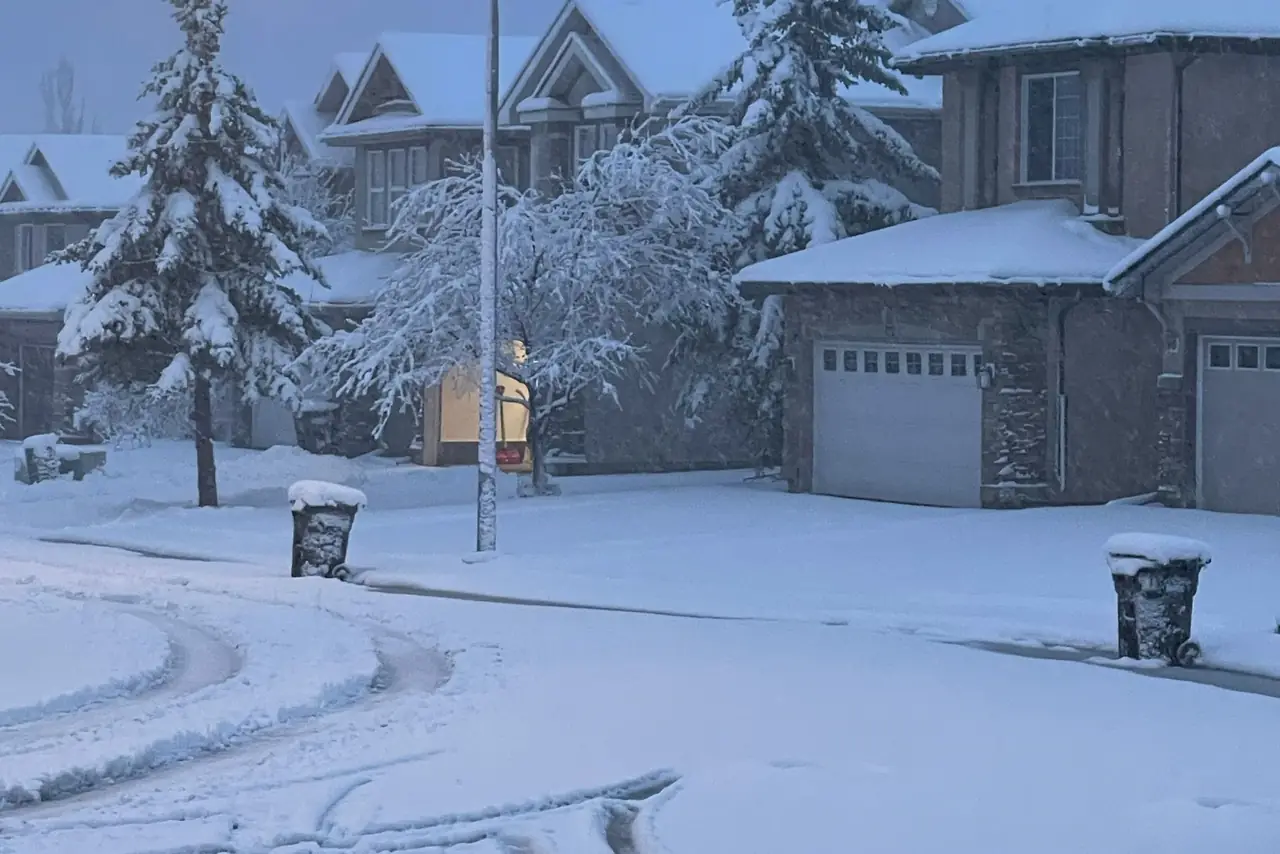 Snow covered residential street in Calgary at twilight with houses and street lights