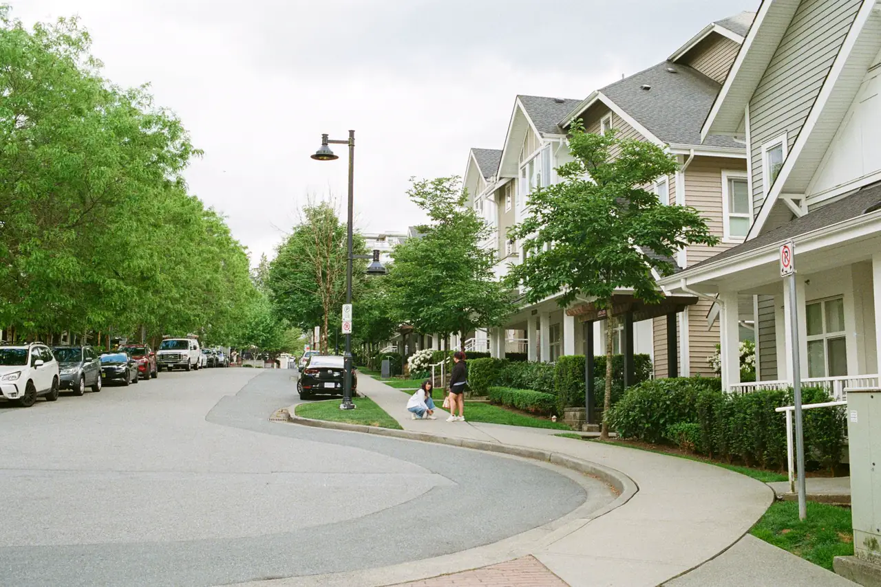 Tree lined Vancouver street with townhouses and families out walking