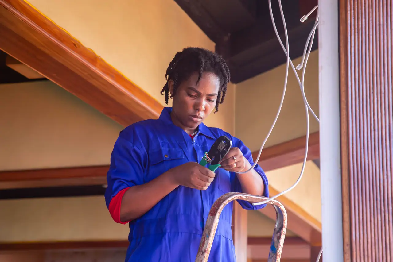 Electrician in blue coveralls works on wiring inside a building