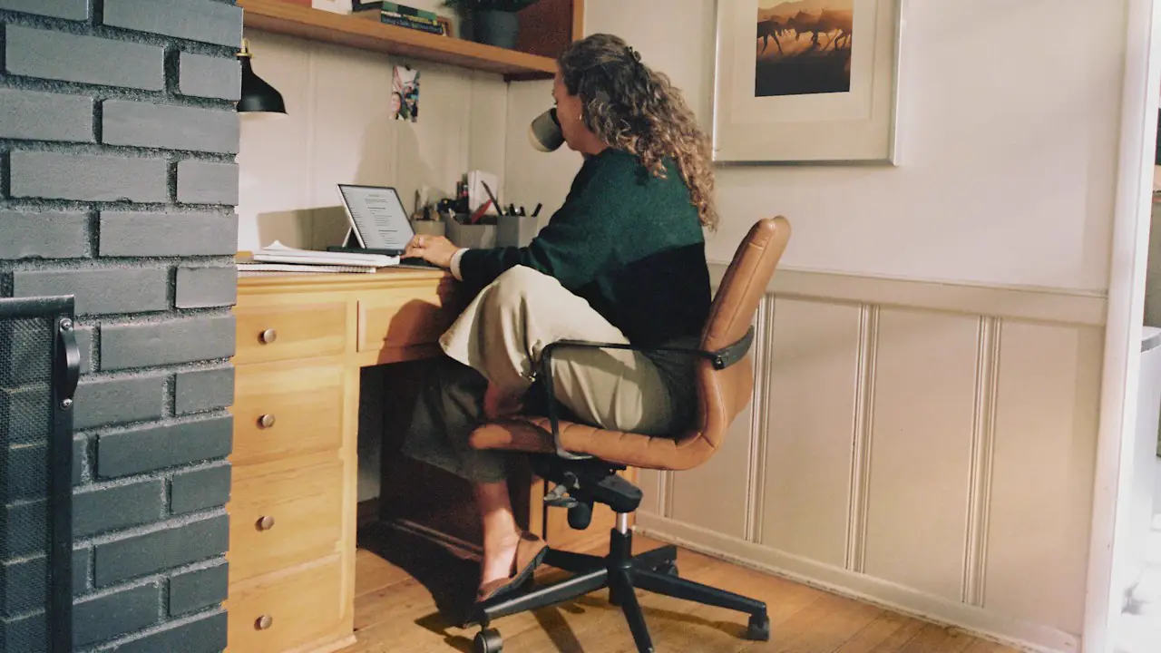 A woman working at a wooden desk in a bright home office