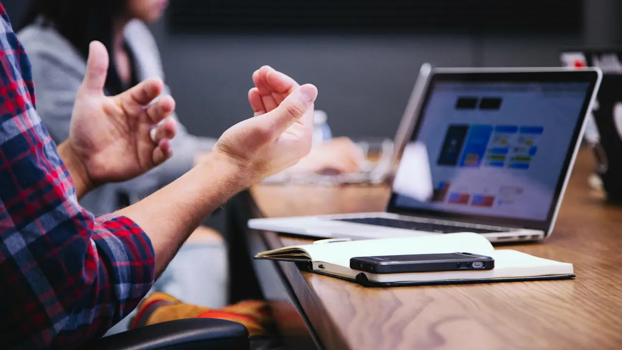 Hands gesturing over a laptop and notebook during a client meeting