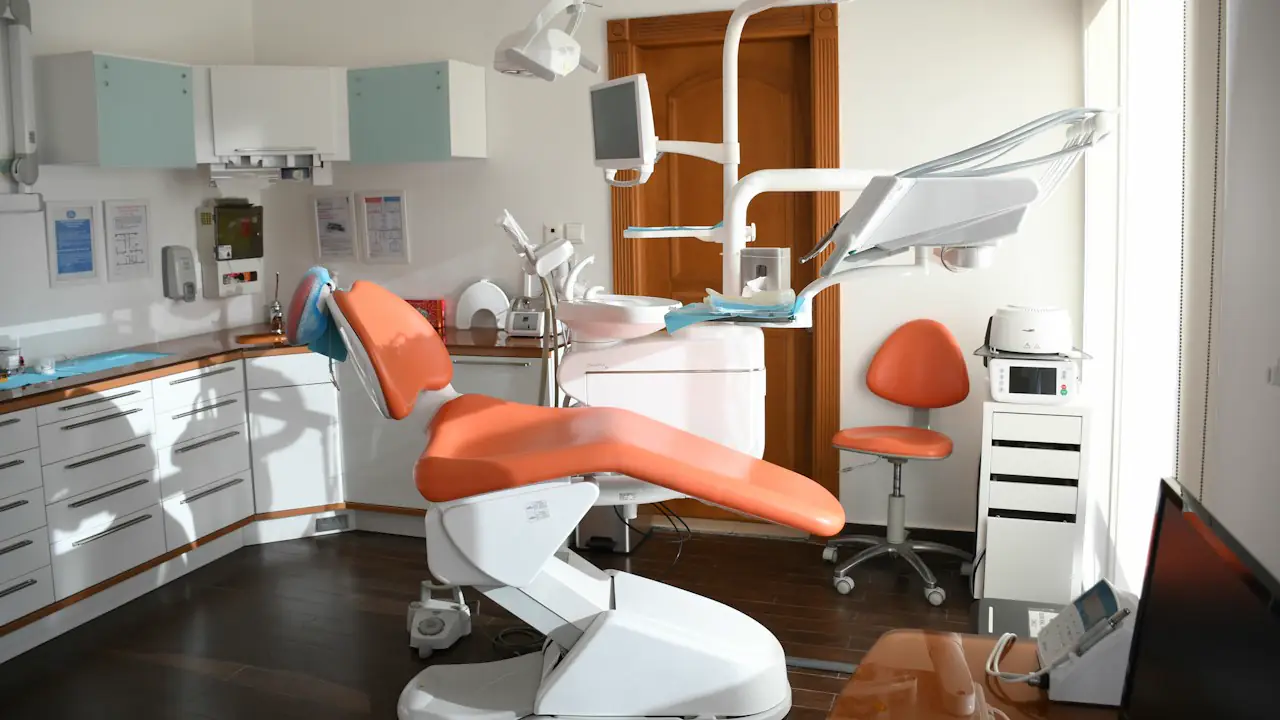 A bright dental treatment room with an orange chair and modern equipment