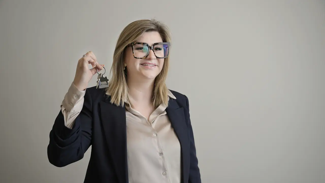 A smiling real estate agent in a blazer holding up a set of house keys