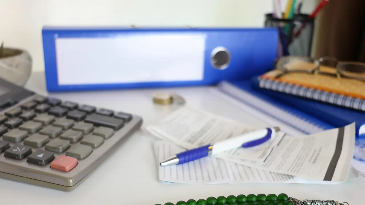 A calculator, binders and receipts on an office desk