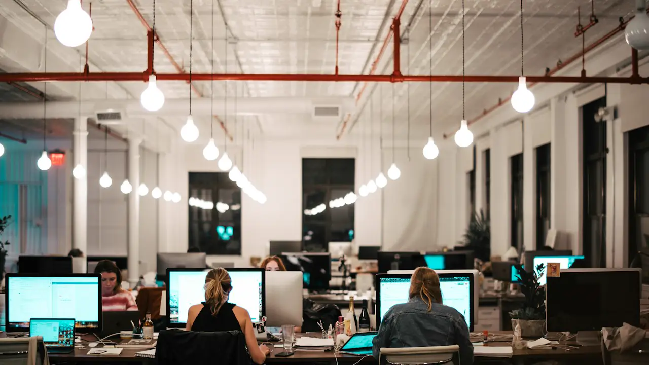 An open plan office with people working at their computers in the evening