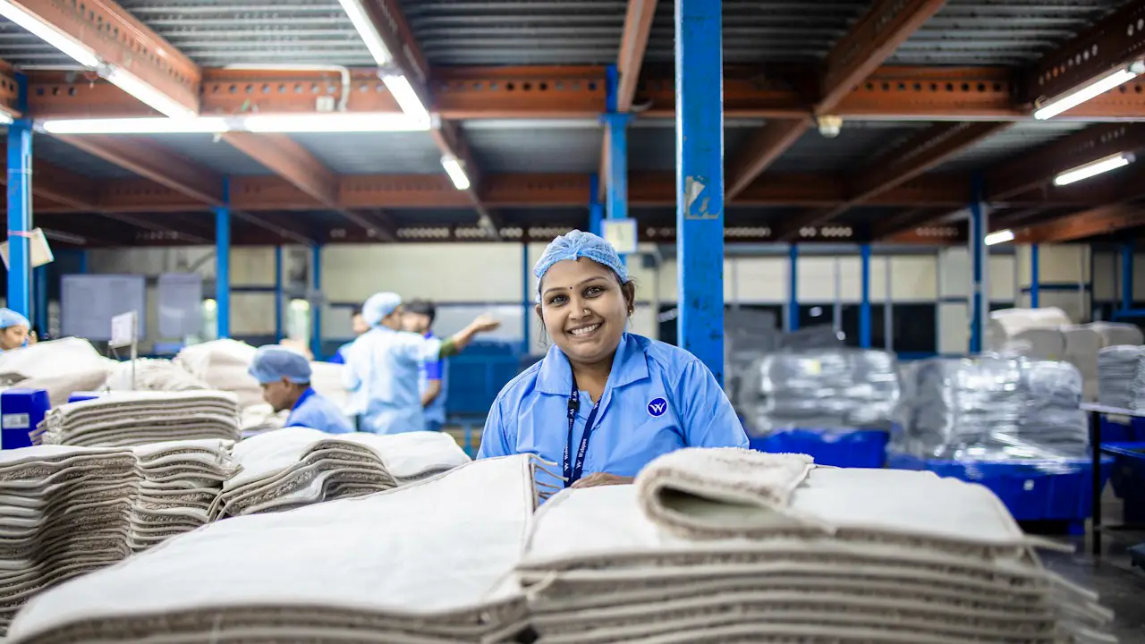 A smiling worker at her station on a busy factory floor
