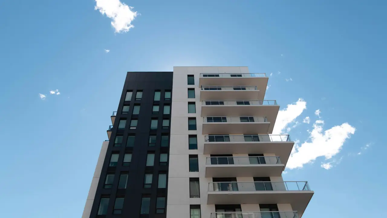 A modern residential tower with wide balconies against a bright blue sky