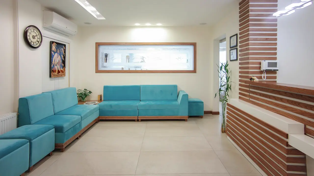 A clean clinic waiting room with teal sofas