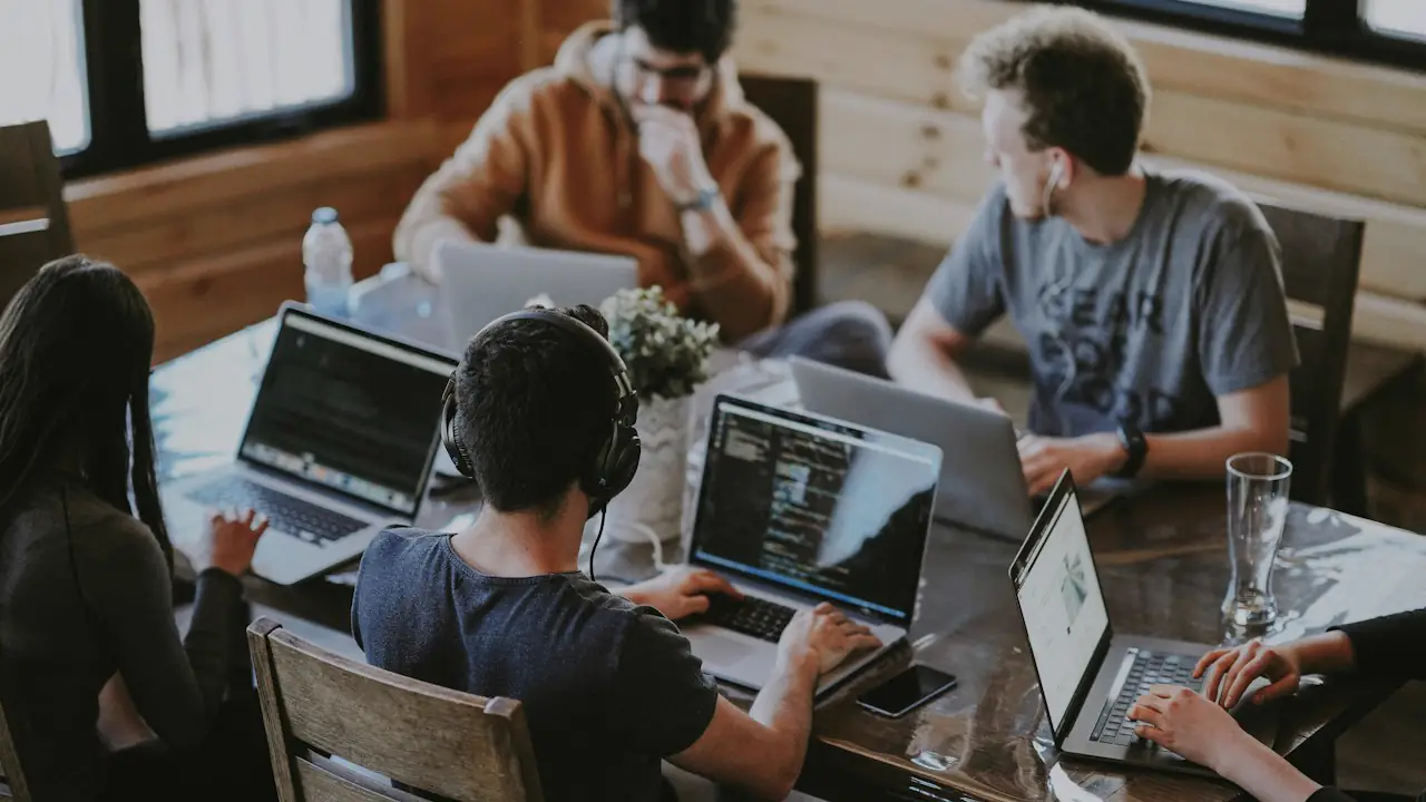 A small team working together at laptops around a wooden table