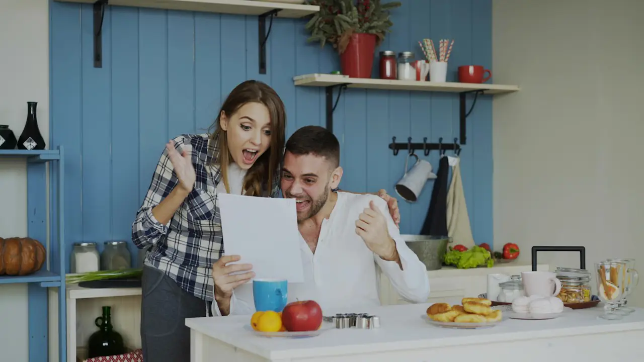 A delighted couple reading a letter together at their kitchen counter