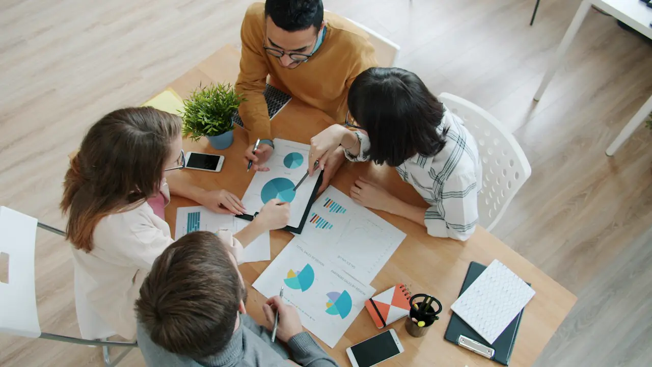 A team working through printed charts around a table, seen from above