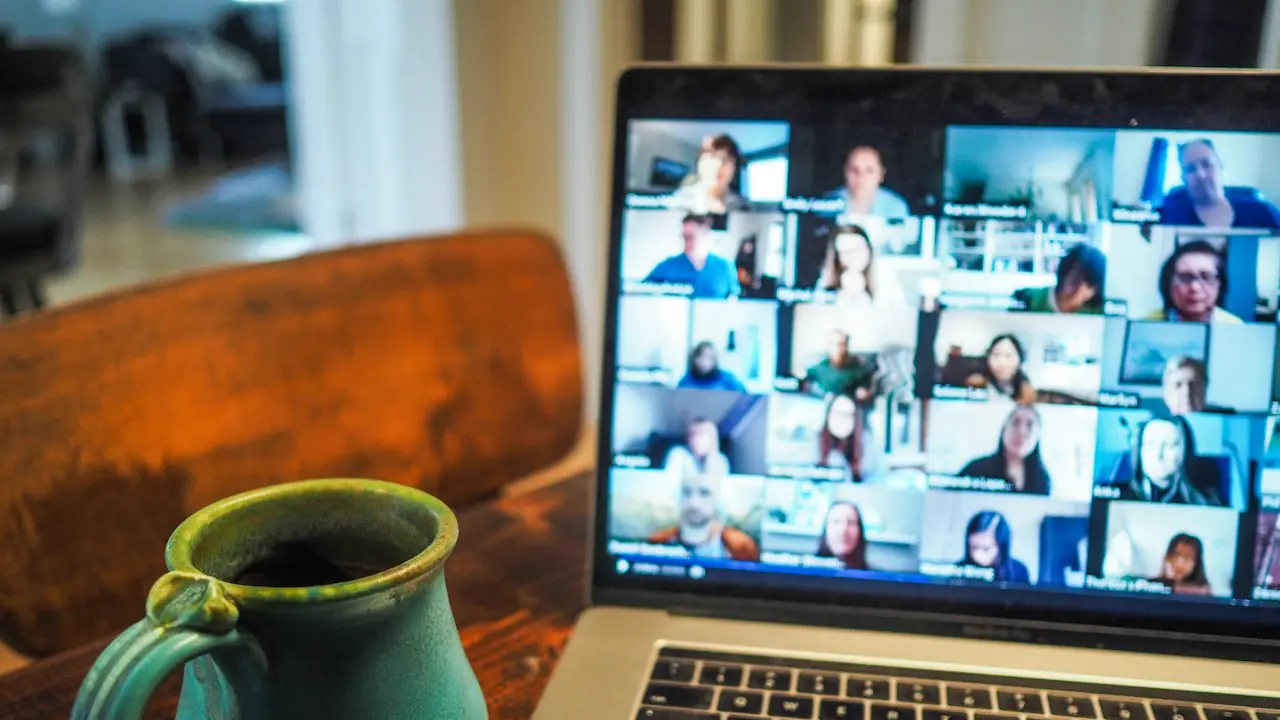 A video call on a laptop beside a green mug