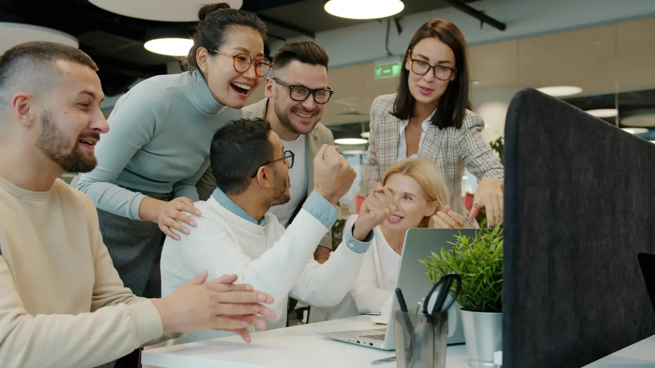 A team celebrating good news together around a computer