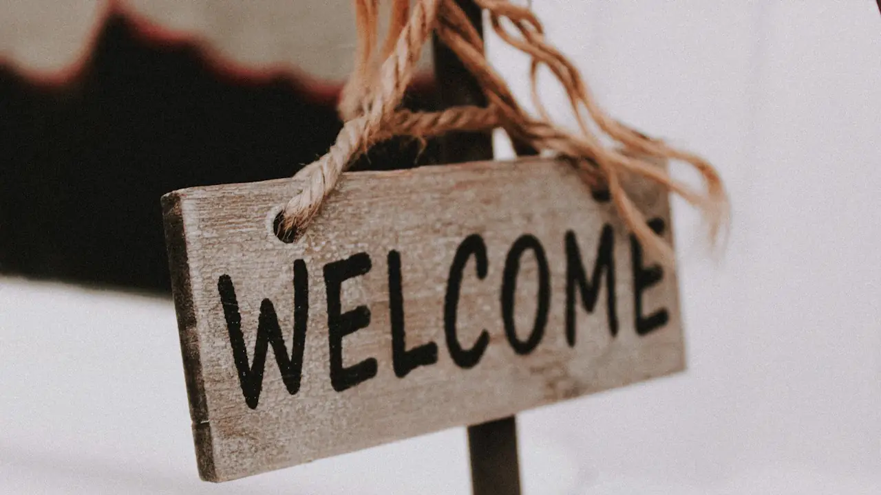 A wooden welcome sign hanging from a rope