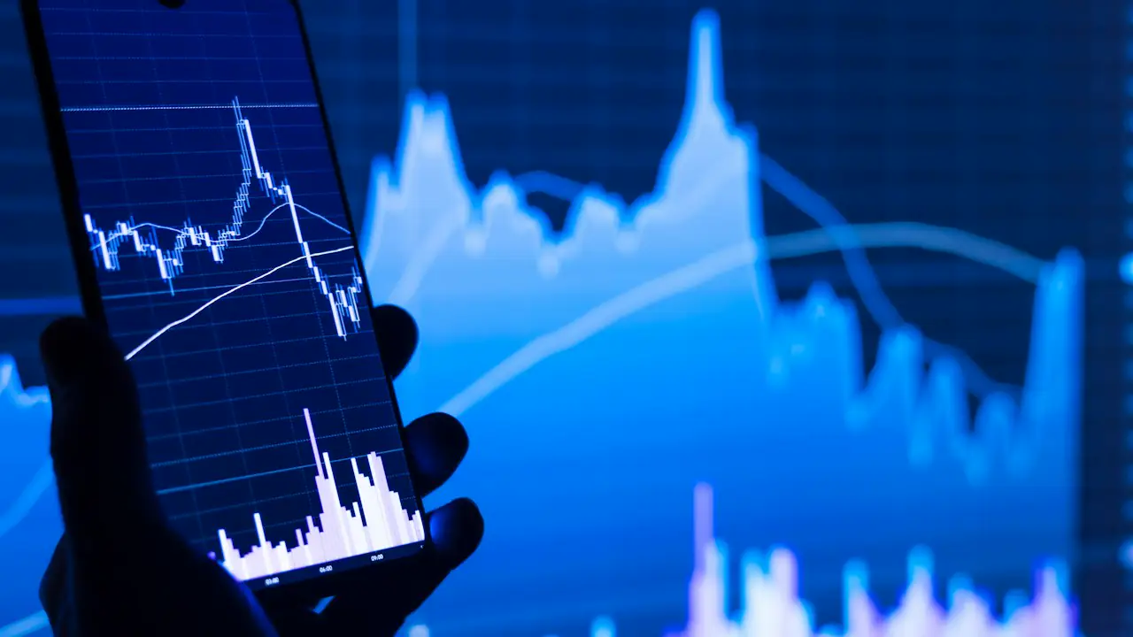 A phone showing a rate chart in front of a large blue chart on a screen