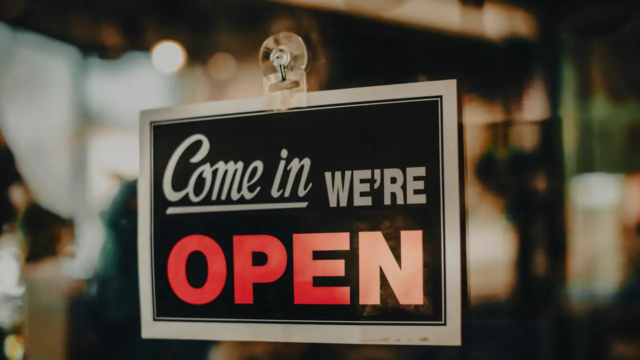 A sign reading come in, we're open hanging in a shop window