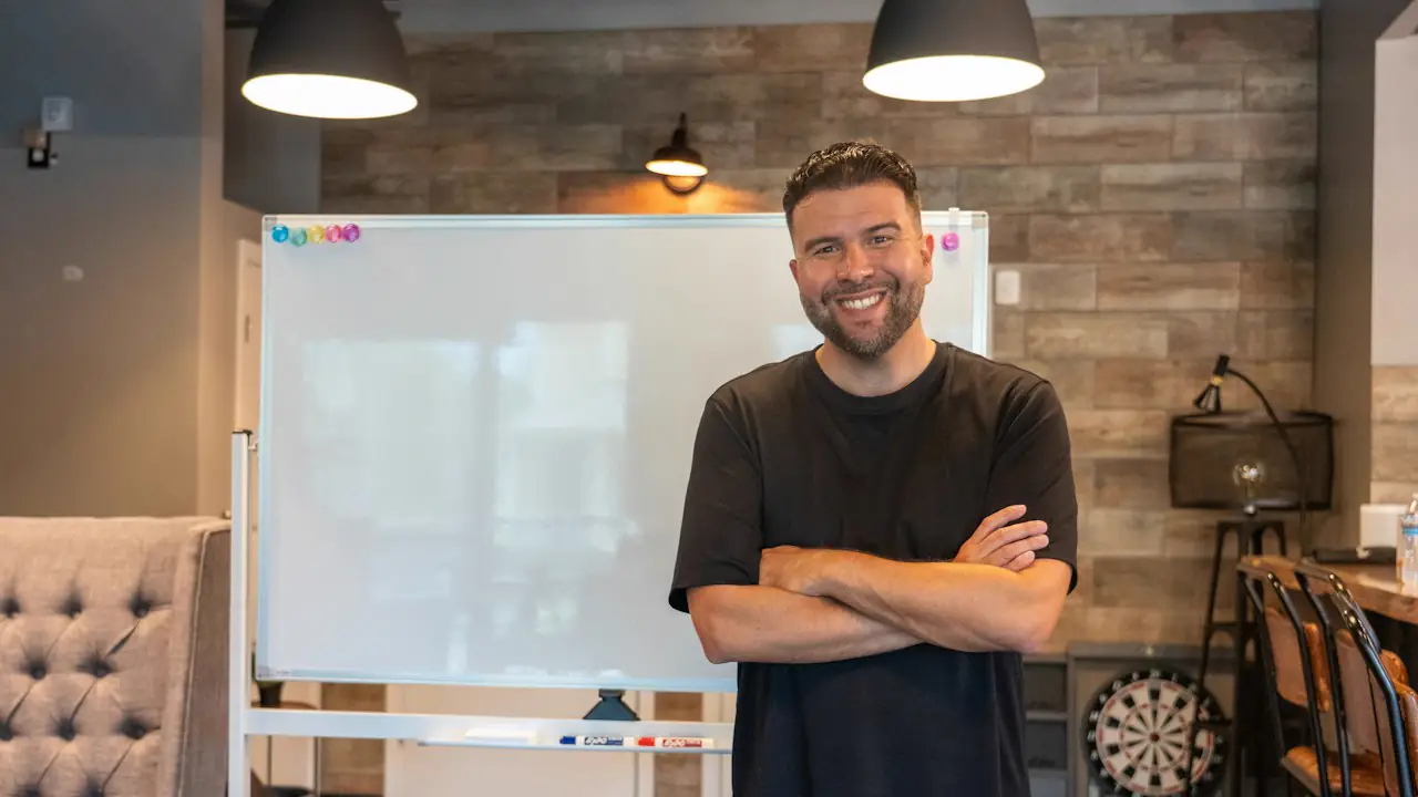 A smiling man with arms folded standing in his newly fitted out workspace