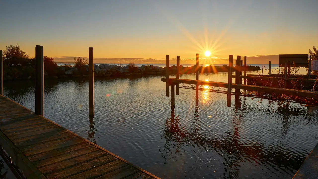 The sun rising over a calm harbour with wooden docks in the foreground
