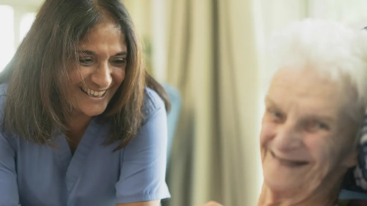 A smiling nurse sharing a laugh with an elderly woman