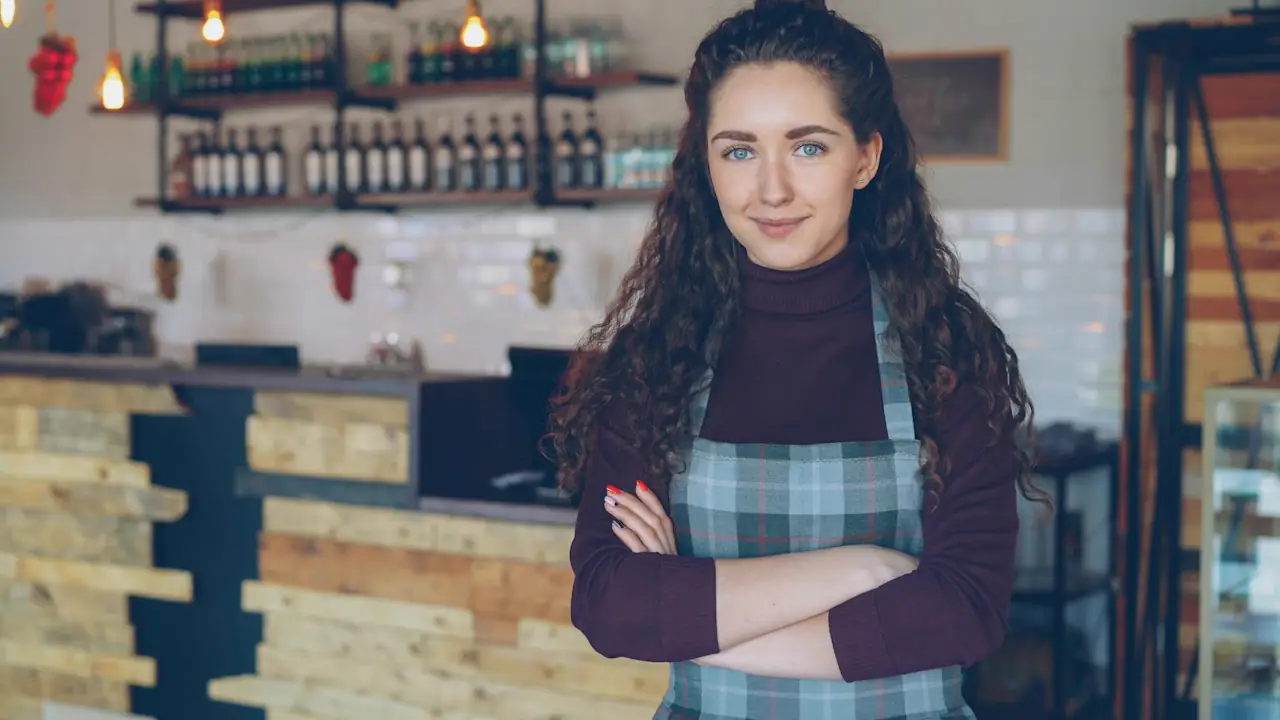 A smiling cafe owner standing in front of her counter