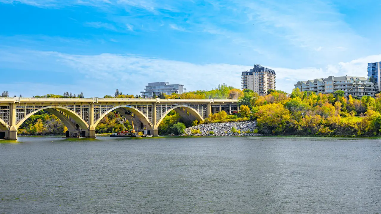 The arches of the Broadway Bridge over the South Saskatchewan River among autumn trees