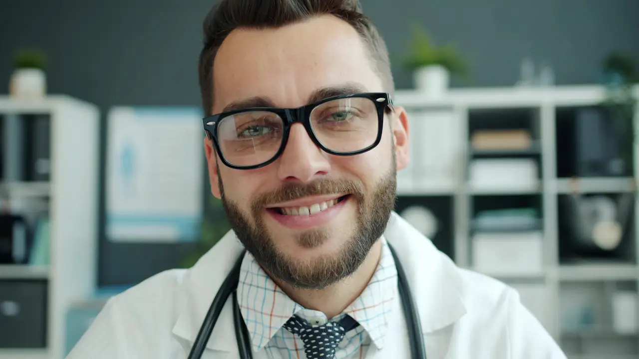 A smiling doctor in glasses and a white coat with a stethoscope
