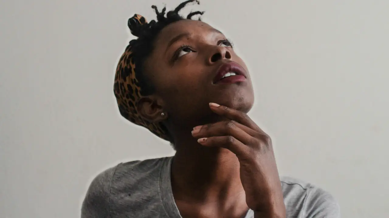 A woman looking up thoughtfully with her chin in her hand