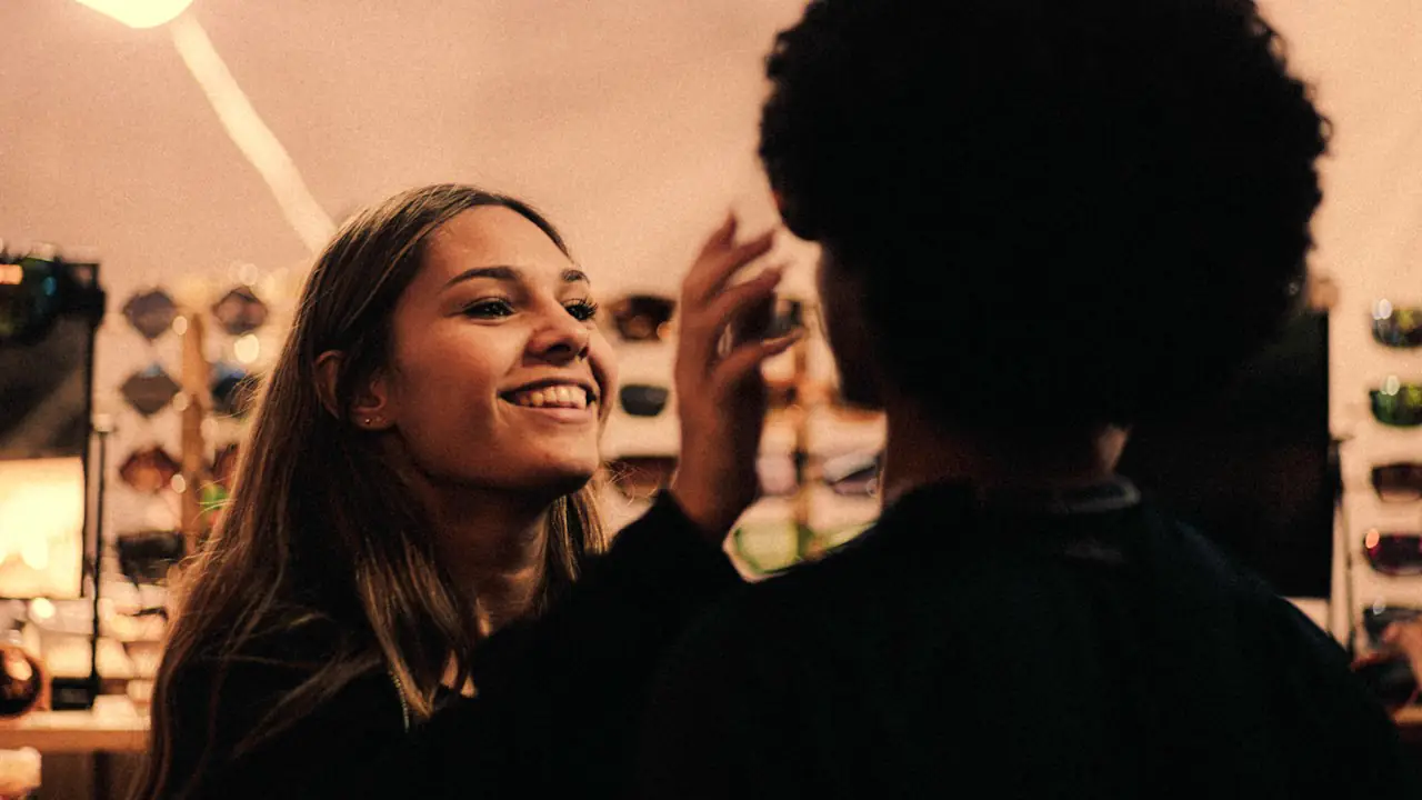 A smiling woman being fitted for new glasses in an eyewear shop