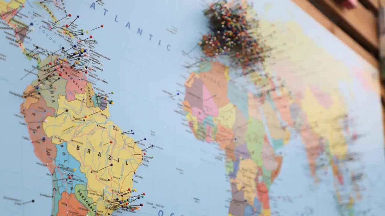 A colourful world map stuck with dozens of pins across several continents