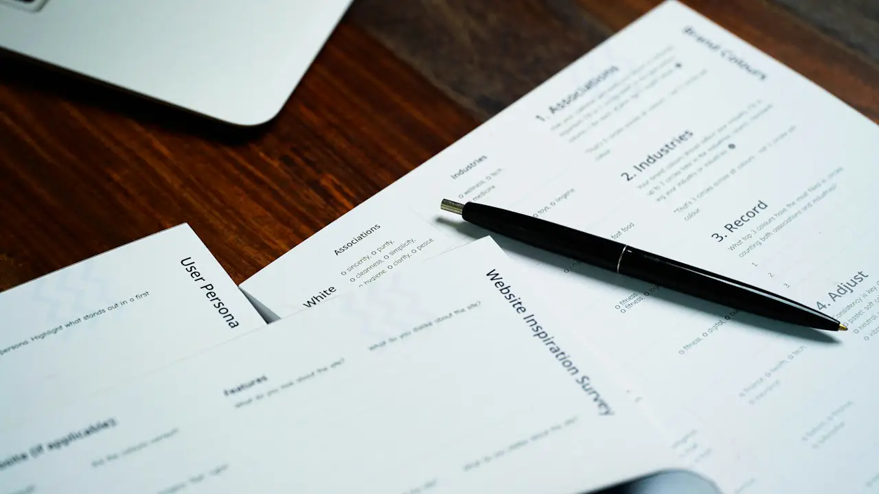 Printed forms and a pen on a wooden desk