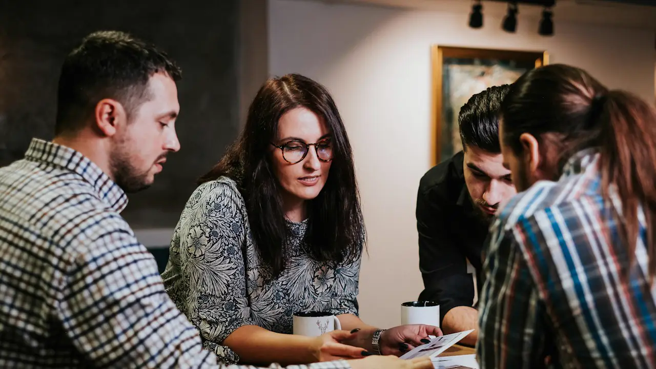Four colleagues gathered around a table going over printed documents together
