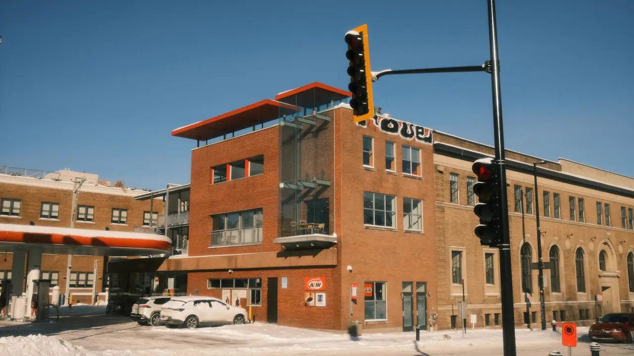 A three storey brick building on a street corner under a clear winter sky