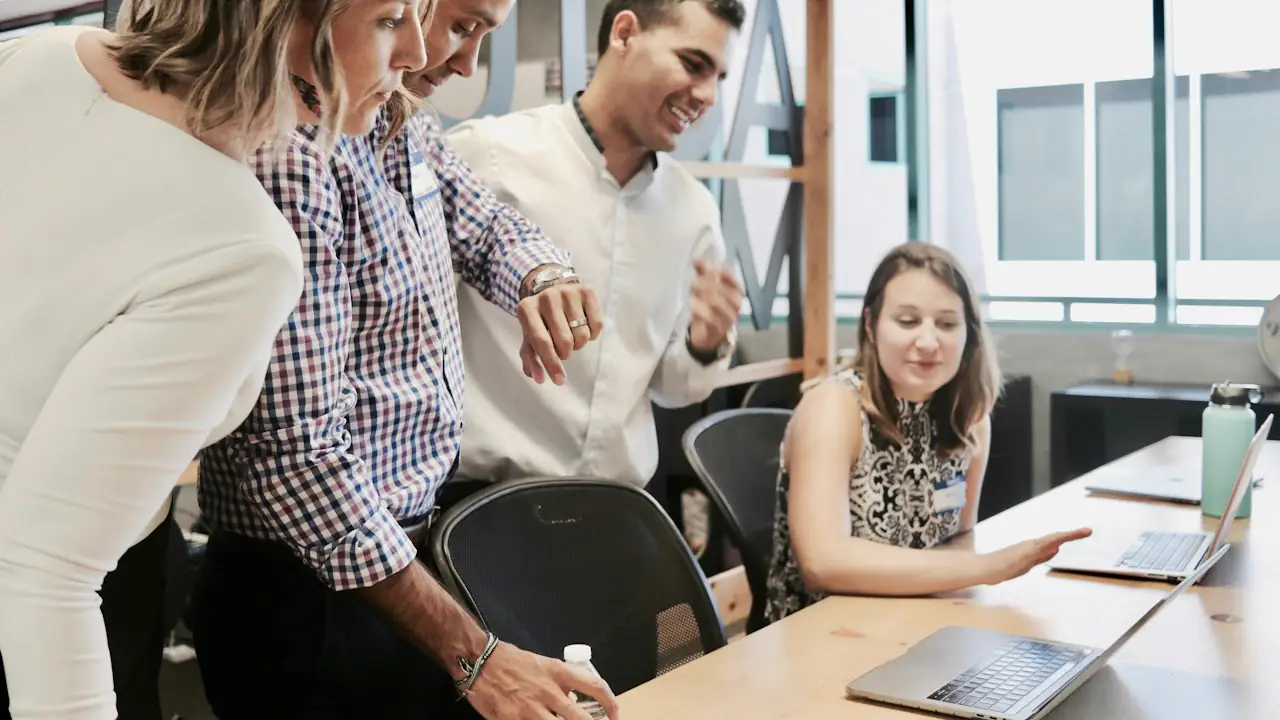 Colleagues gathered around a desk sharing a laugh in a bright office
