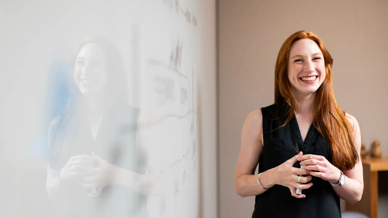 A smiling consultant standing beside a whiteboard covered in notes